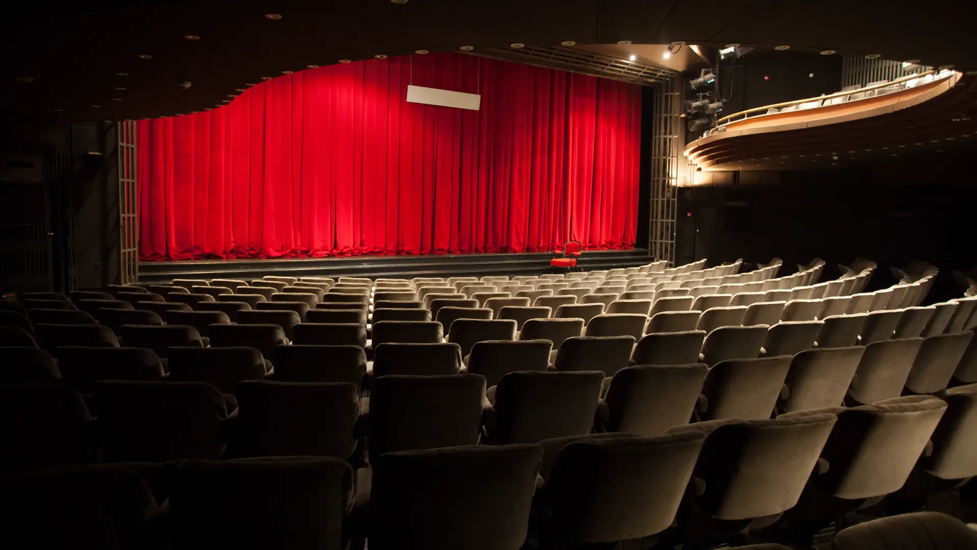 GettyImages-474204411 A theater with rows of seats and red curtains.